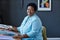 Confident mature African American craftswoman sitting by workplace in studio