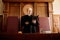 Confident mature blond female judge with open folder standing by desk