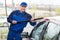 Confident Mature Serviceman Washing Car At Garage