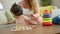 Confident mother and joyful daughter sitting together on the sofa, playing a fun maths game with a puzzle toy, spreading