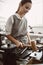 Confident motion. Vertical photo of female jeweler making a silver ring using a hammer