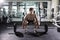 Confident muscular man training squats with barbells over head. Closeup portrait of professional man workout with barbell at gym.