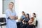 Confident Nurse Standing While Pet Owner Waiting In Clinic