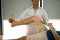 Confident physical therapist helps patient use resistance band stretching out his leg in clinic room