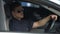 Confident policeman sitting in patrol car and wearing sunglasses, ready for work