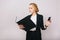 Confident pretty blonde businesswoman in office suit looking at folder in hands, holding phone on white background