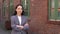 Confident proud young Asian business woman wearing suit posing outside.