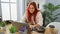 Confident redhead businesswoman, a joyous young worker, smiling as she works online using her laptop in the elegant office