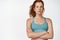 Confident redhead woman in headphones and sportsbra, looking serious and motivated, fitness instructor inviting to