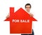 Confident salesman with house for sale sign