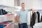 Confident Salesman Leaning On Rack In Clothing Store