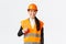 Confident satisfied asian female construction manager in safety helmet, reflective jacket, showing thumbs-up in approval