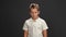 Confident schoolboy teenager in a white t-shirt looks at the camera. Isolated on a gray background. Copy space