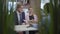 Confident seller woman in formal suit shows information to man and woman customers on her tablet in modern motor show