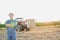 Confident senior farmer standing with arms crossed against tractor in field