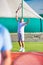 Confident senior man hitting tennis ball with racket on court against clear blue sky