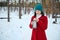 Confident serene delightful dark-haired woman with a vacuum flask enjoying cold winter weather while walking on a snow covered