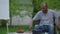 Confident serious disabled man rolling wheelchair to table on summer backyard. Portrait of concentrated African American