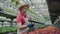 Confident serious male biologist putting pots with flowers into box. Portrait of mid-adult Caucasian man in straw hat