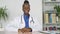 Confident smiling african female doctor looking at camera sitting at workplace.