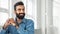 Confident smiling bearded indian man posing at office, looking aside at copy space, sitting at workplace, panorama