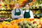 Confident smiling saleswoman standing with trainee salesgirl in greengrocery store