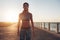 Confident sportswoman standing on a seaside road at evening