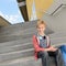 Confident student with tablet sitting on steps