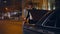 Confident tourist opening car trunk at night. Businessman getting travel luggage