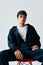 Confident trendy mixed race man sitting on a chair on white background looking to camera