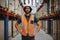 Confident warehouse manager standing in between shelf with hands on waist wearing uniform and hardhat inspecting goods