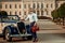 Confident wealthy young man with briefcase near classic convertible