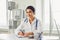 Confident woman doctor pediatrician writes in a clipboard sitting at a table in a white office of the hospital