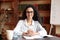 Confident woman in glasses posing sitting at table