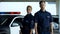 Confident woman and man police officers standing near patrol car, on duty