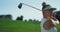 Confident woman playing golf on fairway. Golfer swinging ball at country club.