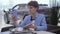 Confident woman with short hair in classic blue formal suit sits at the table talking by cell phone using front camera