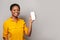 Confident woman showing smartphone with empty blank screen display. Model in yellow shirt with phone on gray studio wall