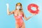 Confident woman in swimsuit holding rubber ring, wearing hygienic face mask and surgical gloves to prevent contagious coronavirus