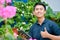 Confident young asian male worker doing research at outdoor`s garden farm give thumb up and holding tablet computer. modern garden