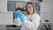 Confident young blonde woman scientist, beaming, delicately measuring liquids in a test tube at her lab table. engrossed in ground