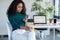 Confident young business woman sending messages with mobile phone sitting in the office