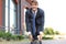 Confident young businessman in business suit on longboard hurrying to his office, on the street in the city