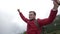 Confident young climber with open arms celebrating the achievement on top of mountain after a trekking hike -