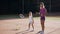 Confident young coach throwing ball and little girl hitting ball on the court.
