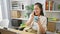 Confident young hispanic woman worker talking business over phone, sipping espresso in office room, exuding elegance amidst a busy