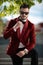 Confident young man wearing red velvet tuxedo and arranging bowtie