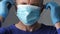 Confident young surgeon doctor in latex protective gloves wearing medical mask on face. Man professional medic in