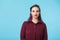 Confident young woman standing over blue background