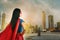 Confident young woman wearing superhero costume and beautiful cityscape on background